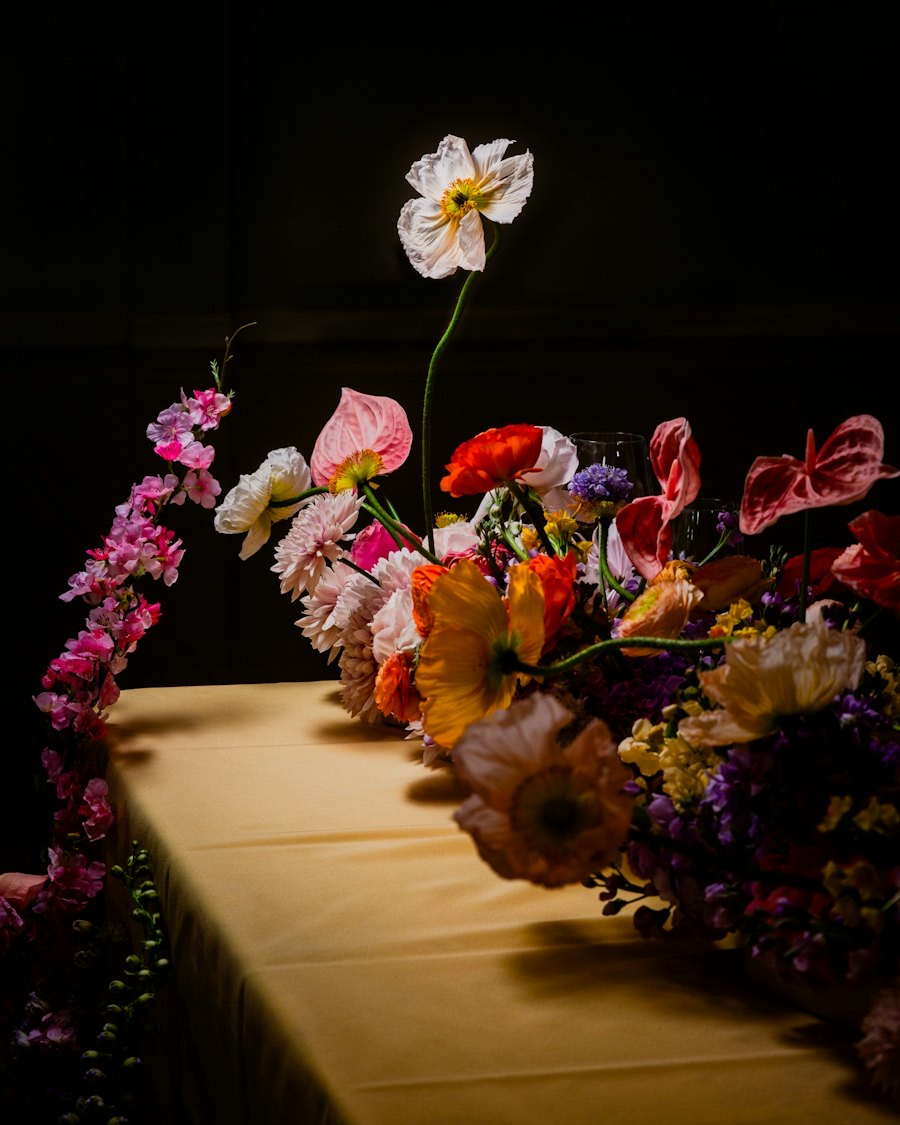 Long dinner table runner of vivid mixed flowers in low light